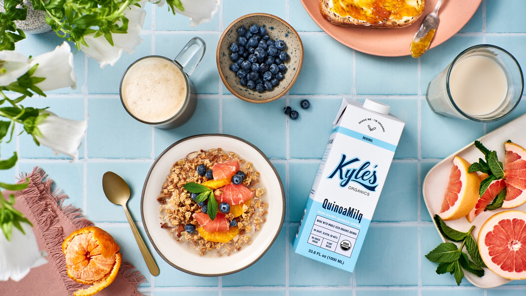Breakfast with Kyle's Quinoa Milk carton, bowl of granola, and fruits.